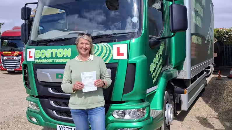 Image of Lindy in front of a green HGV after passing her HGV training course with Lifft